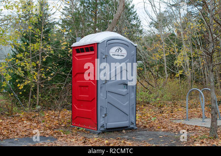 Tragbare Badezimmer chemische Toilette Toilette Toilette mit einem Poly Kunststoff Gehäuse mit Tür in bewaldeten Gebiet von Falmouth Shining Sea Bikeway Stockfoto