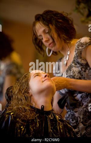 Ein weiblicher Friseur locken Haare für eine weibliche Kunden im Friseursalon Stockfoto