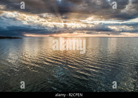 Schönen Sonnenuntergang über dem Wasser mit Sonnenstrahlen über der Wolken Stockfoto