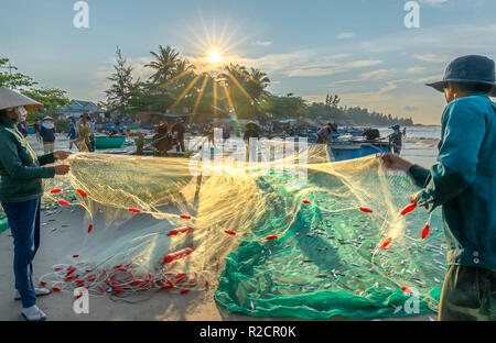 Fischer machen nach dem Fangen im Küstenfischereidorf Fischernetz. Das ist harte Arbeit, aber viele Familien in Phan Thiet, Stockfoto