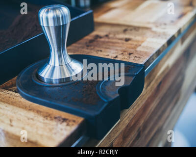 Edelstahl/Stampfer und Kaffee boden auf hölzernen Tisch im Café. Stockfoto