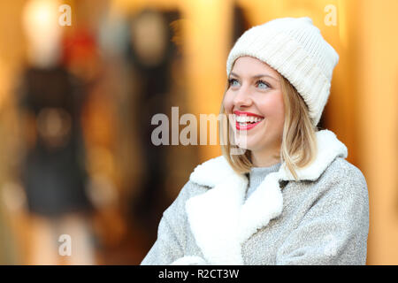 Glückliche Frau denken, die oben stehend in einem Einkaufszentrum im Winter Stockfoto