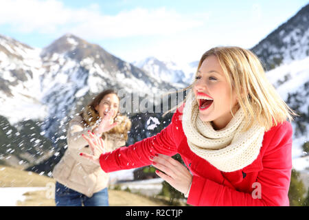 Zwei lustige Freunde scherzen das Werfen mit Schneebällen im Berg auf Winterurlaub Stockfoto