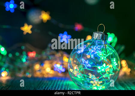 Weihnachten dekoratives Glas Kugel gegen defokussierten Girlande lichter Hintergrund für das neue Jahr Einrichtung Stockfoto