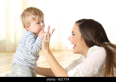 Baby Küssen seine Mutter den Finger auf dem Boden in einem Zimmer Stockfoto