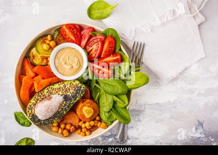 Vegan buddha Schüssel mit gebackenem Gemüse, Kichererbsen, Avocado und tahini Dressing auf einem weißen Hintergrund, Ansicht von oben, kopieren. Stockfoto