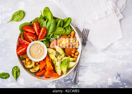 Vegan buddha Schüssel mit gebackenem Gemüse, Kichererbsen, Avocado und tahini Dressing auf einem weißen Hintergrund, Ansicht von oben, kopieren. Stockfoto