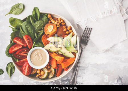 Vegan buddha Schüssel mit gebackenem Gemüse, Kichererbsen, Avocado und tahini Dressing auf einem weißen Hintergrund, Ansicht von oben, kopieren. Stockfoto