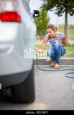 Junge Frau Kontrolle der Auto Luftdruck aufpumpen Es Stockfoto