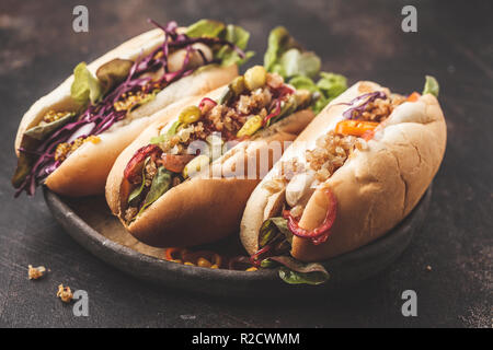 Hot dogs mit verschiedenen Toppings auf einem dunklen Hintergrund, Ansicht von oben. Traditionelle American Food Konzept. Stockfoto