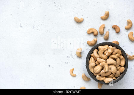 Cashew Nüsse in der Schale auf grauem Beton Hintergrund mit Kopie Platz für Text. Ansicht von oben, gesunde vegetarische Kost Stockfoto