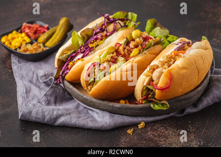 Hot dogs mit verschiedenen Toppings auf einem dunklen Hintergrund, Ansicht von oben. Traditionelle American Food Konzept. Stockfoto