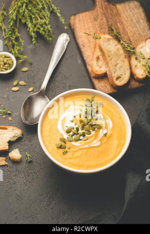 Kürbissuppe garniert mit pepitas und Sahne auf Schwarz konkreten Hintergrund, Ansicht von oben, selektiver Fokus Stockfoto