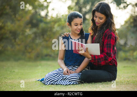 Glückliche Frau und Tochter in einem Garten ein Buch lesen. Stockfoto