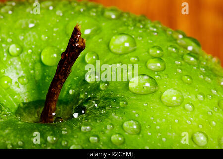 Enge Makro einer Green Apple top in Wassertropfen in der Nähe der Spindel des Apple abgedeckt. Lebhaftes Grün auf der Apple und einen Pool von Wasser in den Stamm Tal. Stockfoto