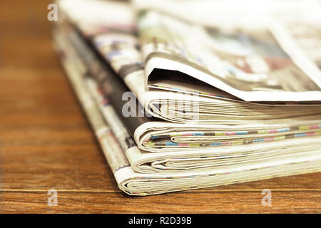 Stapel von frischen Morgen Zeitungen auf Holztisch im Büro. Business Nachrichten in den Tageszeitungen. Gefaltete und gestapelte Gelbe Seiten mit selektiven Fokus. Stockfoto