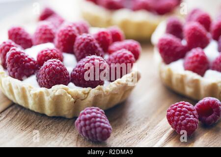 Das Mädchen hält in ihrer Hände lecker, nützliche und schöne Törtchen mit Himbeeren Stockfoto