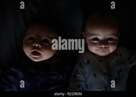 Baby Zwillingsbrüder in der Dunkelheit Stockfoto