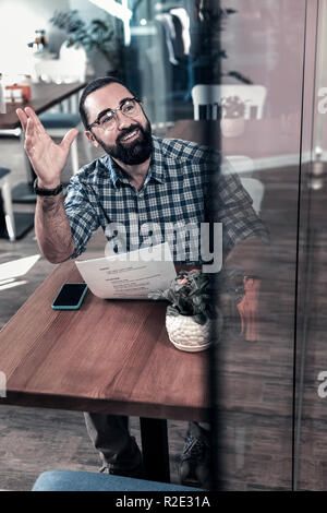 Angenehme Mann, Quadrat shirt Aufruf Kellner im Restaurant Stockfoto