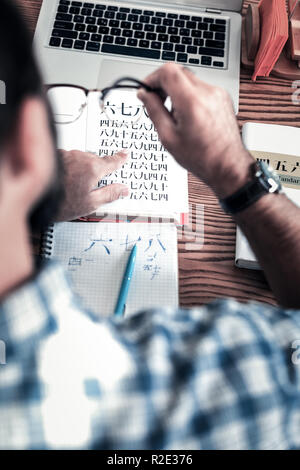 Blick von oben auf die Mann im Quadrat Shirt und Hand watch Hieroglyphen studieren Stockfoto