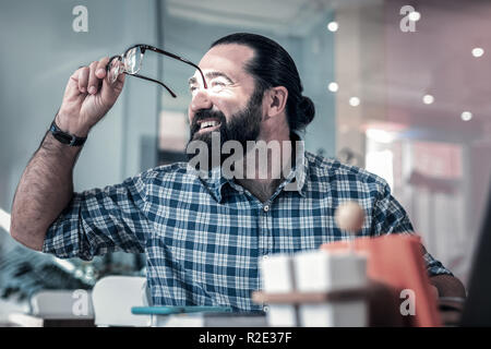 Der bärtige Mann mit Squared shirt Suchen in das Fenster Stockfoto