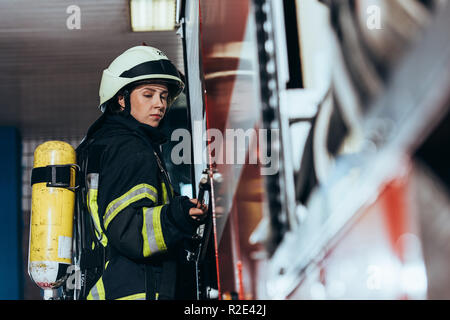 Seitenansicht der weiblichen Feuerwehrmann mit Feuerlöscher auf Schließen Lkw im Fire Station Stockfoto