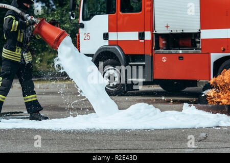 Teilansicht der Feuerwehrmann Löschmittel Feuer mit Schaum auf der Straße Stockfoto