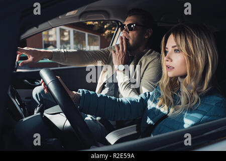 Schockiert mann Richtung zeigen zu Freundin auf Fahrersitz im Auto. Stockfoto