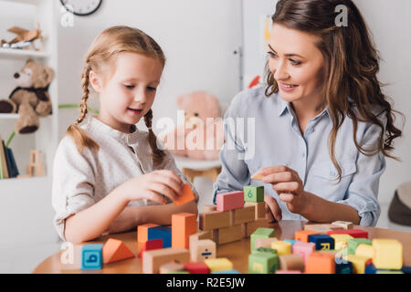 Glückliche Mutter spielt Bausteine mit entzückenden kleinen Kind Stockfoto