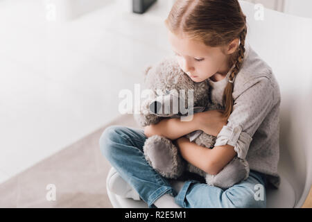 Hohe Betrachtungswinkel von depressiven Kind umarmt ihren teddy bear Stockfoto