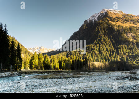 Rocky Mountain Landschaft im frühen Winter mit schneebedeckten Gipfeln und bunten Wald und einem Bergbach im Vordergrund mit Eis und Reim auf die r Stockfoto