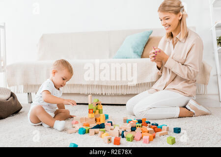 Adorable Kleinkind spielen mit bunten Würfel und Mutter im Kinderzimmer Stockfoto