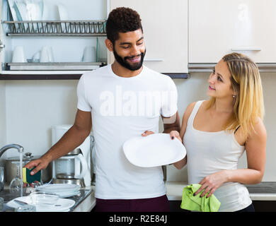 Schwarzer Mann mit dem Lächeln amerikanische weiße Frau abstauben in der heimischen Küche Stockfoto