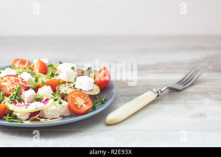 Gesund lecker lecker Salat mit Tomaten, Radieschen, Käse, Sprossen und Sesam in der Platte auf hellem Holztisch, flacher Tiefe des Feldes. Stockfoto