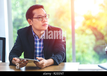 Asiatische Geschäftsmann weg schauen Denken mit Tablet für Vision und Technologie Konzept. Stockfoto
