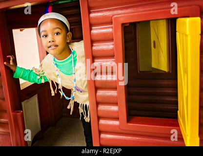 Ein Pre-school student Einblicke aus einer Kabine Playhouse anmelden, während in einem Indianer Kostüm, November 21, 2012, in Columbus, Mississippi gekleidet. Stockfoto