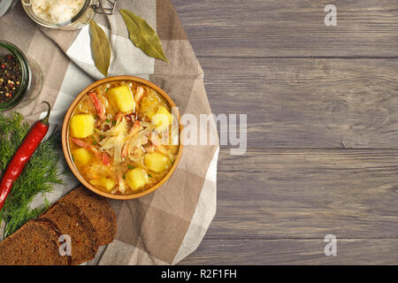 Sauerkraut Suppe in der Schüssel mit schwarzem Pfeffer und Lorbeer auf der Seite. Overhead auf rustikalem Holz fotografiert. Platz kopieren. Stockfoto