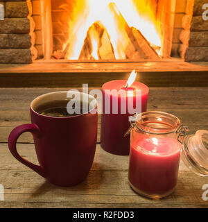 Rot Tasse mit heißem Tee und Kerzen, in der Nähe der gemütlichen Kamin, im Landhaus, winter Urlaub, horizontal. Stockfoto