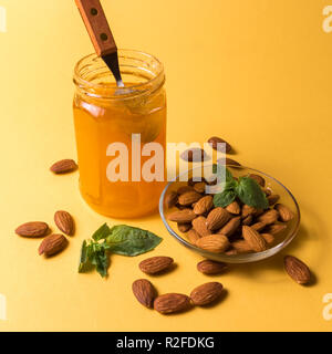 Vorderansicht des Hausgemachte Marmelade im Glas und Mandel Muttern gegen den gelben Hintergrund. Stockfoto