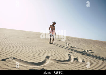 In Glück mitten in der Wüste mit Sand Dünen verloren. Junge glückliche junge Teenager genießen Ferien am Strand. klaren blauen Himmel im Hintergrund. Badeanzüge und Zeichen in den Sand. Sommer Tag Stockfoto