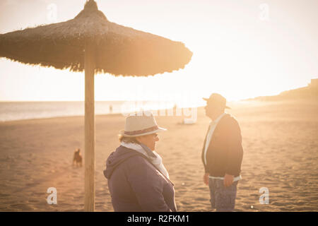 Paar getrennt, Mann und Frau, ältere Menschen zu verschiedenen Richtungen getrennt mit Hintergrundbeleuchtung aus den Sonnenuntergang. Dachte Konzept im Frühjahr in der Nähe des Meeres. Stockfoto