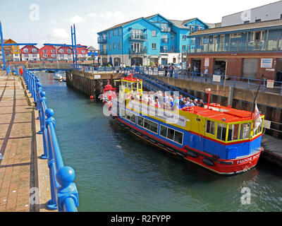 Ein buntes Boot im Eingang das alte Dock in Exmouth, die mittlerweile eine Marina mit modernen Gehäuse, Devon, England, UK umgeben Stockfoto