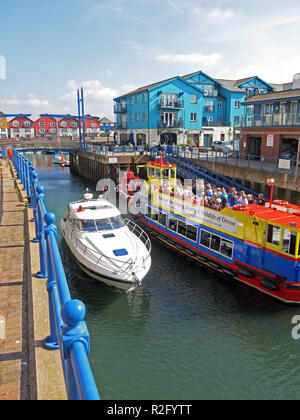 Ein buntes Boot im Eingang das alte Dock in Exmouth, die mittlerweile eine Marina mit modernen Gehäuse, Devon, England, UK umgeben Stockfoto