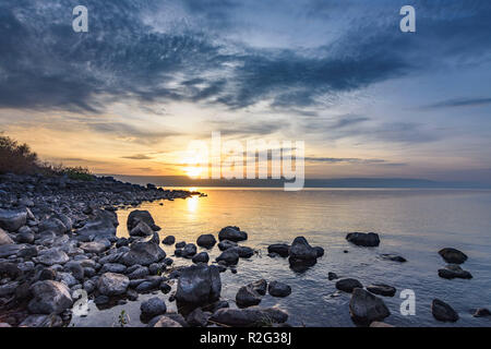 Landschaft der Felsenküste mit ruhigen Wellen und Sonnenuntergang am See Genezareth, Israel. Stockfoto