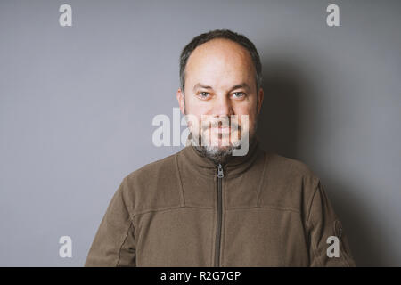 Mann mittleren Alters mit kurzen dunklen Haaren und grauem Bart lächelnd Stockfoto