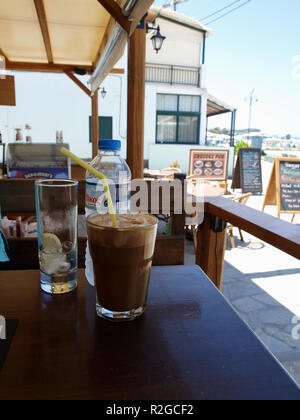 Glas Frappé und eine Flasche Wasser im Beachside Cafe in Roda, Korfu, Griechenland serviert. Stockfoto