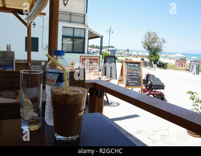 Glas Frappé und eine Flasche Wasser im Beachside Cafe in Roda, Korfu, Griechenland serviert. Stockfoto