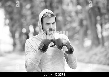 Boxer Übung auf die frische Luft. Knowckout. Mann stanzen. Für den Erfolg kämpfen. Mann in Boxhandschuhe und Haube auf natürliche Landschaft. Ausbildung seine Boxen Fähigkeiten. Geboren, um zu kämpfen. Kraft und Energie. Stockfoto