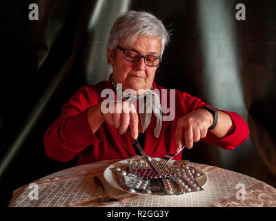 Konzept der Medizin und Gesundheit. Eine ältere Frau, die mehrere Tabletten von Pillen auf ihren Teller zu essen Stockfoto