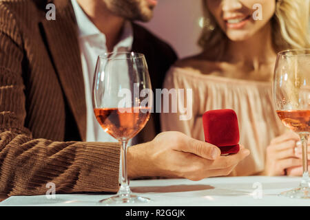 Zugeschnittenes Bild des Menschen schlägt Freundin während romantisches Abendessen in Restaurant Stockfoto